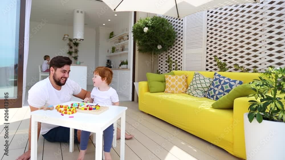 happy father and son playing games on patio at home at summer sunny day
