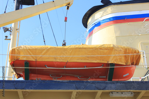 Orange Lifeboat on Russian Naval Ship. View of Lifeboat for Emergency Situationon Deck of Marine Ship. Emergency Evacuation and Life Saving Equipment Onboard Ship