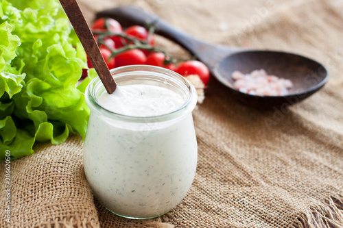 Photo Cream and herbs dressing in glass jar