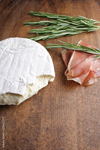 cheese brie and prosciutto jamon ham wooden background rosemary