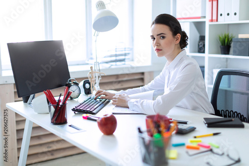 Young girl in the office working with documents at the computer.