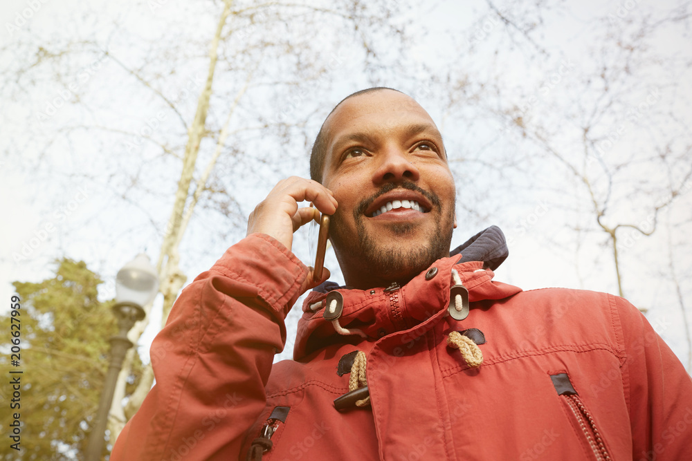 Young happy smiling urban hipster man wearing informal clothes and using smart phone. Hipster holding mobile smartphone hand using for make call friends. Blurred
