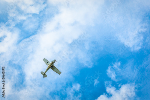 Small plane flying in the sky with beautiful white clouds