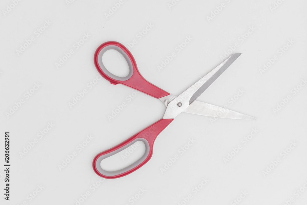 Opened scissors with red helve against a white background