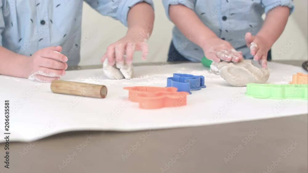 Two boys preparing dough for cookies together with their mum Two boys preparing dough for cookies together with their mum