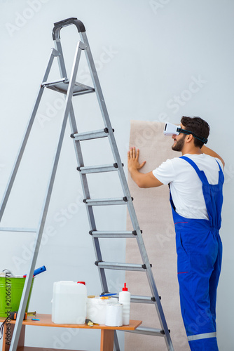 Man with VR glasses gluing wallpaper