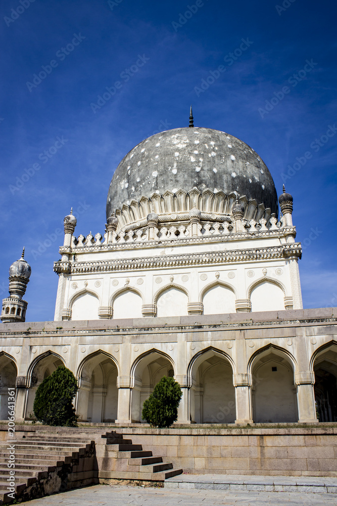 One of the White and Grey Buildings of the Qutb Shahi Tombs with Beautiful Mughal Architecture against a Blue Sky in Hyderabad, India