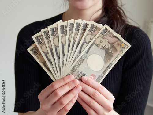 1万円札を10万円分手に持つ女性 photo