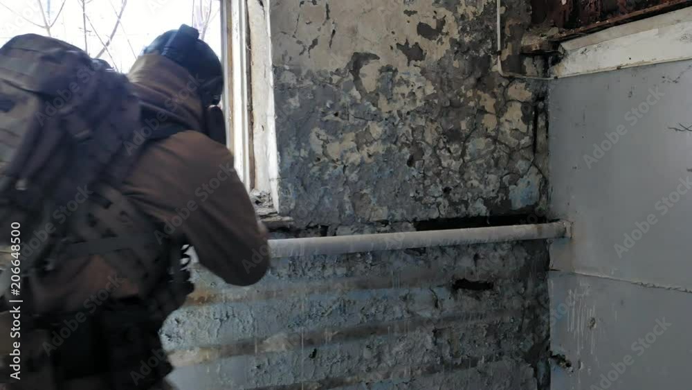 Soldiers in camouflage with a military weapon aiming through the rifle sight through the window of an old building, the military concept