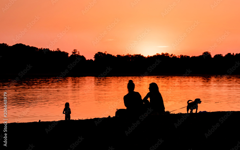 Kids and families are having fun at a lake under sunset