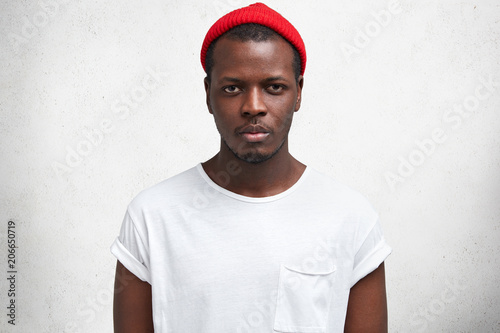 Portrait of handsome dark skinned male, has sullen look, being unhappy as has quarrels with close person, wears stylish clothes, isolated on white background. Confident African American man indoor
