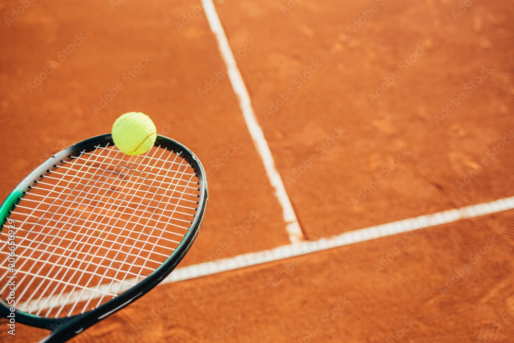 Close up of tennis racket and ball on clay court