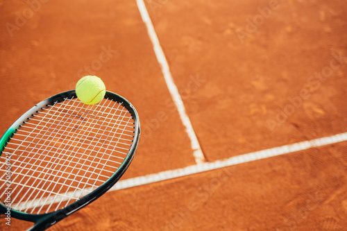 Close up of tennis racket and ball on clay court © yossarian6