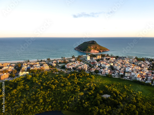 aerial landscape photo of Recreio dos Bandeirantes beach during sunset, with views of Chico Mendes park and the Pontal Stone bathed by orange sunlight photo