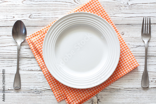Empty plate with untensils on white wood  background
