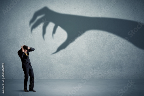 Fotobehang Business person afraid of a big monster claw shadow concept on background