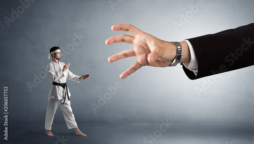 Small karate man fighting with big hand