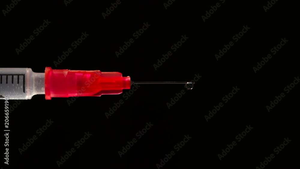 MACRO: A drop on a end of needle of a syringe - side view MACRO: A drop on a end of needle of a syringe - side view
