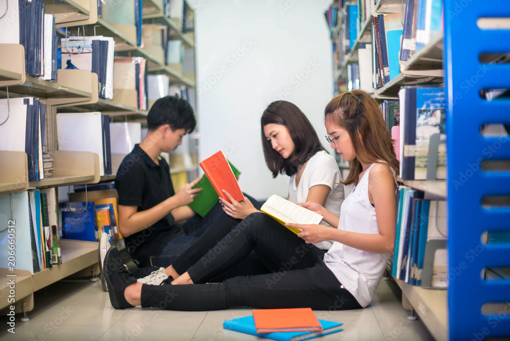 education groups , school and people concept - Cheerful university students with read a book and doing group report  in Library.; Asia university.