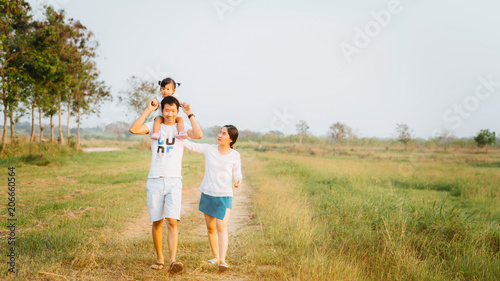 a happy family of three people, mother, father and child in green garden; asian family are happy working in the parks; travel nature trip