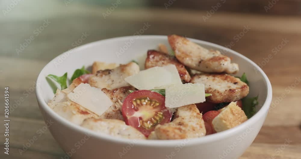 Slow motion closeup parmesan flakes falling on caesar salad Slow motion closeup parmesan flakes falling on caesar salad