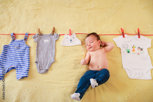 Little baby hanging with clothes on rope. Concept of funny photo session for babies.