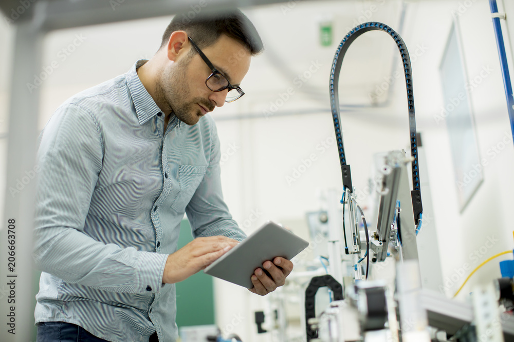 Handsome young man in the electronic workshop holding digital tablet Handsome young man in the electronic workshop holding digital tablet