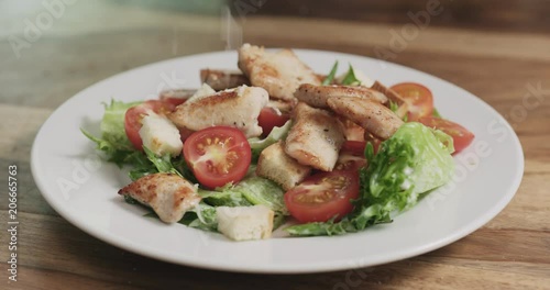 Slow motion closeup parmesan flakes falling on caesar salad photo