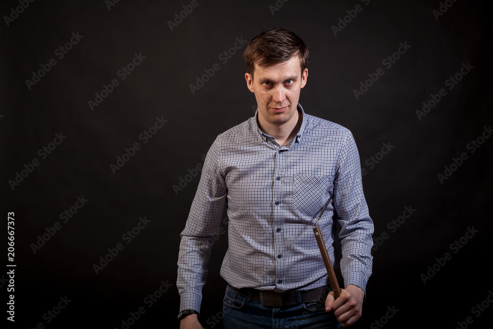 Dark-haired man in a plaid shirt .holds a nunchuck  in his hands .on black isolated background