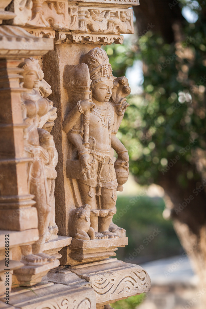Obraz premium The four-hands embodiment of god Vishnu executed in a stone in the form of a bas-relief on a wall of one of temples in Khajuraho.
