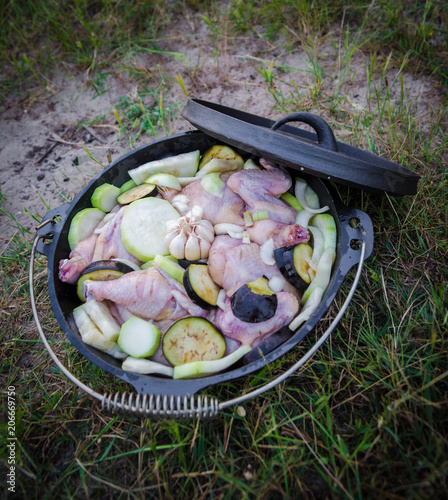 Fresh chicken, aubergine and sqaush stew in cast iron pot or dutch oven to be cooked on campfire photo