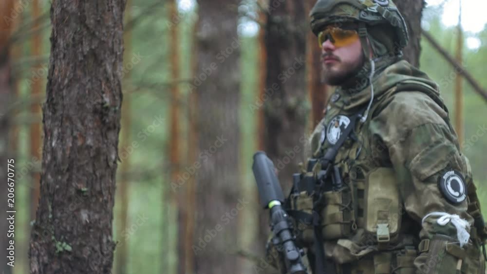 Soldiers in camouflage with combat weapons are being fired in the shelter of the forest, the military concept Soldiers in camouflage with combat weapons are being fired in the shelter of the forest, the military concept