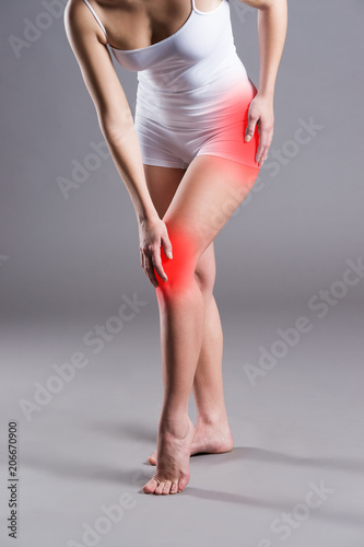 Foto Woman with pain in thigh and knee on gray background