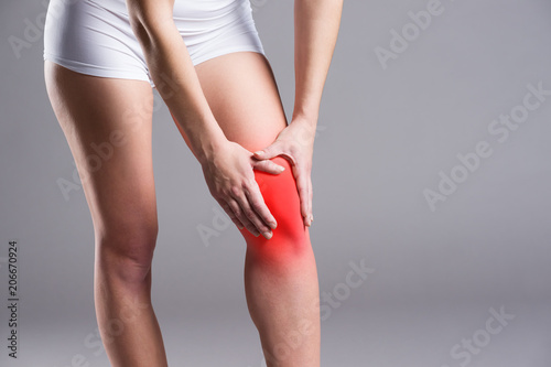 Pain in knee, joint inflammation, on gray background