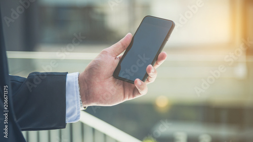 Hand of businessman holding mobile phone with blur background
