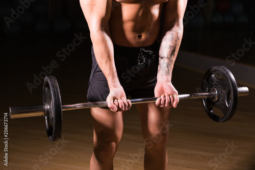 Handsome power athletic man with barbell. Strong bodybuilder with six pack, perfect abs, shoulders, biceps, triceps and chest