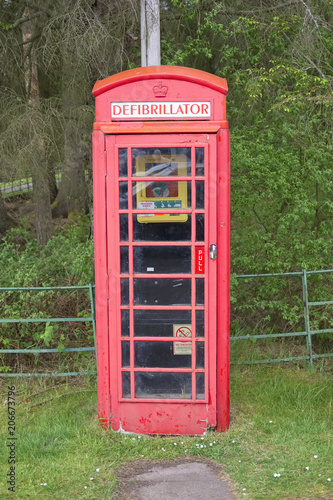 Defibrillator in telephone phone booth box red vintage save life heart attack emergency help in rural countryside Scotland uk © Richard Johnson