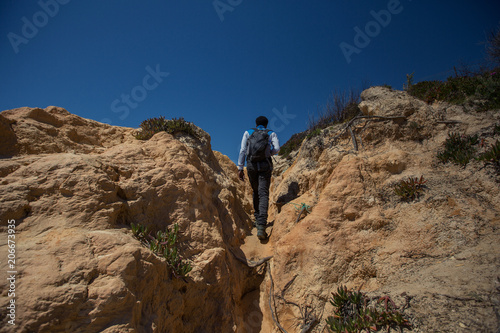 Traveller man walking on cliff beach, enjoy travel holiday. Algarve, Portugal