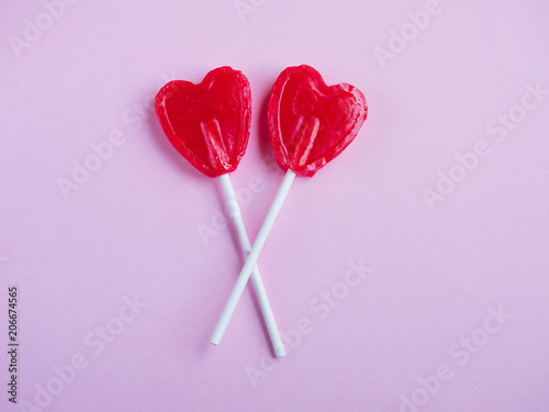 Two red heart lollipop on pink background