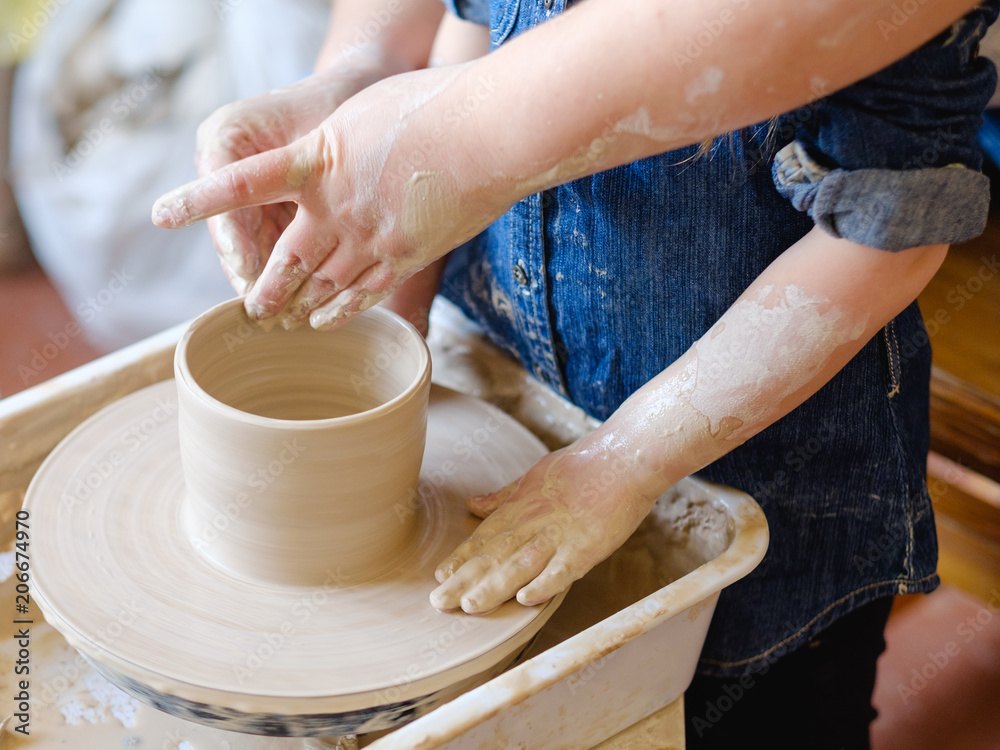 pottery workshop. handmade craft. artisan teaching a child girl how to form and shape clay on potter wheel