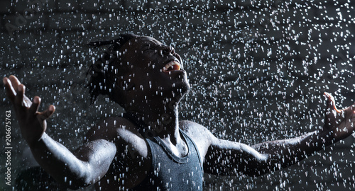 Photography African man shout under rain at the night thunderstorm with raised hands