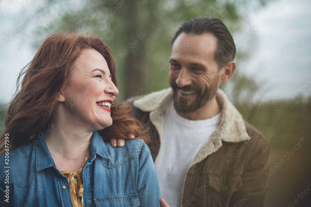 Cheerful loving couple is dating outdoor. Husband is embracing wife with tenderness and smiling Cheerful loving couple is dating outdoor. Husband is embracing wife with tenderness and smiling