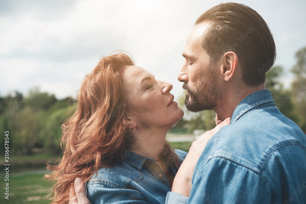 Passionate married couple is bonding to each other in the nature. Beautiful lake is on background Passionate married couple is bonding to each other in the nature. Beautiful lake is on background