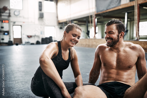 Smiling young couple sitting together on a gym floor