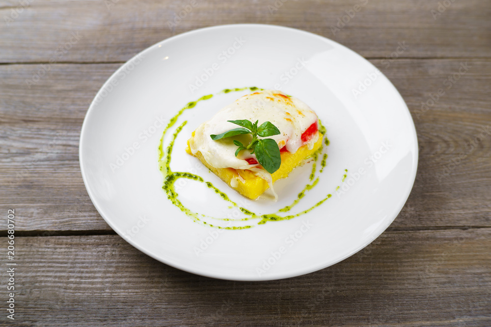 Baked corn polenta with melted mozzarella cheese, tomato and pesto sauce. Delicious meals, gluten-free food, healthy eating Baked corn polenta with melted mozzarella cheese, tomato and pesto sauce. Delicious meals, gluten-free food, healthy eating