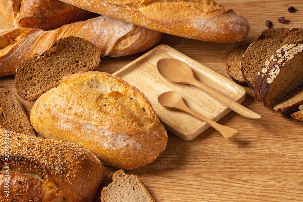 Various kind of delicious breads are arranged on brown wood background with copy space.