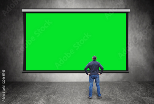Man stands in front of big empty green screen