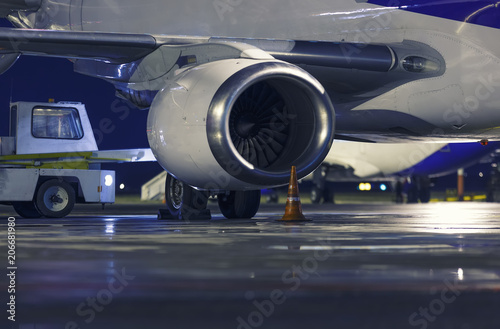 aircraft engine depth of field close-up, night airport, plane and loading car in the background