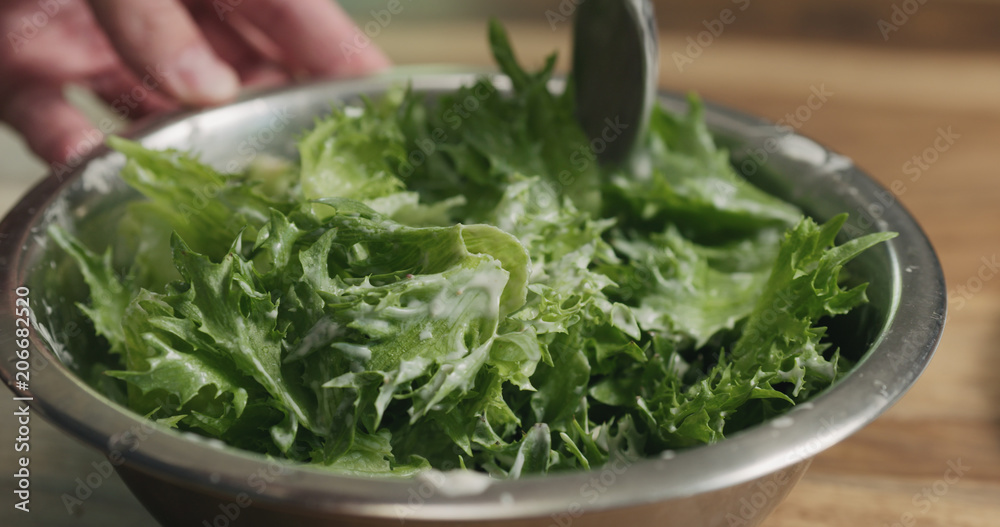 closeup mixing frillis salad leaves with caesar sauce closeup mixing frillis salad leaves with caesar sauce