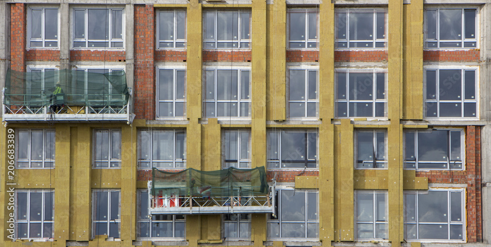 Facade builders warm the walls of a modern high-rise building